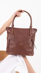 Cartera tipo shopper de tamaño grande, confeccionada en símil cuero con textura efecto croco. Presenta dos bolsillos frontales con cierre metálico en disposición angular, cierre superior principal, bolsillo trasero con cierre, doble asa corta para llevar al hombro y correa larga desmontable y regulable.