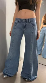 Jean de tiro bajo con corte wide leg y costuras verticales decorativas en el frente. Presenta un lavado azul clásico y ruedo desflecado.