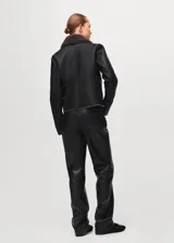 Chaqueta estilo aviador de cuero sintético color negro, con interior y cuello de corderito sintético en tono gris oscuro. Cuenta con cierre frontal cruzado, bolsillos con cierre y detalles de hebillas en las muñecas.