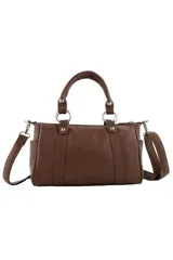 Cartera de mano color bordó con doble asa corta, correa larga ajustable y extraíble, y detalle de tachas metálicas verticales en el frente. Incluye un aplique metálico decorativo en forma de labios con strass en la parte superior central.