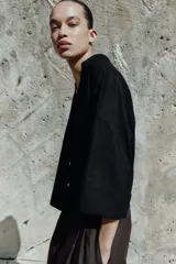 Camisa de corte holgado confeccionada en mezcla de lino, con estampado de rayas verticales en color marrón y blanco. Presenta cuello solapa, escote en pico, cierre frontal con botones y mangas amplias por debajo del codo con puños definidos.