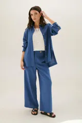 Pantalón de lino azul de corte recto y amplio, con cintura elastizada, cierre de cremallera y botón. Presenta detalles de pespunte blanco en los bordes de los bolsillos.