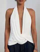Top halter blanco con escote profundo en V, espalda descubierta, diseño fluido y detalle drapeado con efecto cruzado en la cintura.