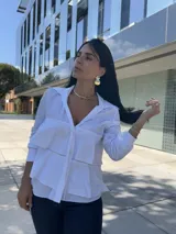 Camisa azul marino de manga larga con cuello camisero y cierre de botones. Presenta volantes horizontales en la parte delantera.