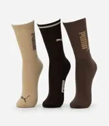 Kit de tres pares de medias deportivas Puma de caña larga. Incluye un par beige con logo Puma en el tobillo, un par negro con dos rayas blancas en el puño y logo Puma en el tobillo, y un par marrón con el lettering "PUMA" en el lateral.