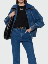 Campera de jean Balmain con cierre frontal, cuello alto y puños elásticos fruncidos. Presenta un diseño estructurado con hombros caídos y bolsillos laterales.