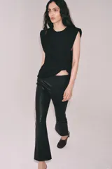 Top de punto negro con cuello redondo, manga sisa, hombreras y detalle de pliegues en la parte delantera.