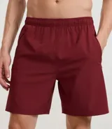 Bermuda deportiva gris con cintura elástica, cordón de ajuste, bolsillos con cremallera, recorte lateral con agujeritos y abertura en el bajo.