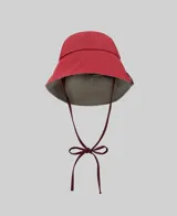 Sombrero tipo bucket reversible, con una cara en color rojo y otra en color gris. Cuenta con tiras ajustables para atar bajo la barbilla y etiqueta con logo en el lateral.