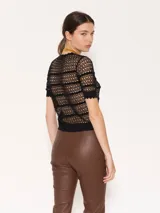 Top de tejido crochet color beige, con cuello redondo y mangas cortas con terminación ondulada.