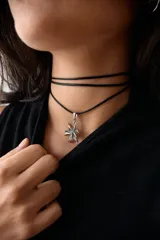 Collar con dije de acero quirúrgico en forma de flor de lirio, montado sobre un tiento de cuero encerado largo.