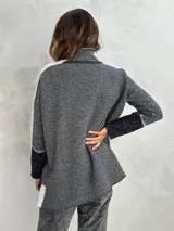 Sweater de punto con patrón de espiga en tonos beige y marrón, cuello alto, mangas largas con detalles en naranja y puños marrones.