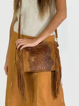 Bandolera marrón de cuero con solapa con textura símil cocodrilo y flecos.