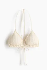 Top de bikini triangular forrado, color beige, con textura gofrada y relleno extraíble. Cuenta con tiras finas para anudar en la nuca y en la espalda.