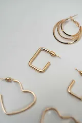 Set de tres pares de aros dorados con diferentes diseños: aros tipo argolla triple, aros rectangulares y aros con forma de corazón.