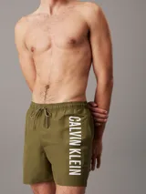 Short de baño verde militar con cintura elástica ajustable con cordón y logo de Calvin Klein estampado en blanco en la pierna izquierda.
