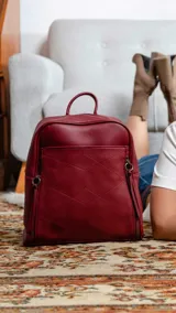 Mochila de cuero sintético color azul con diseño acolchado de rombos en el frente. Cuenta con bolsillo frontal con broche magnético, asa de mano superior y correas regulables. El compartimento principal incluye bolsillos internos con cierre y divisiones.