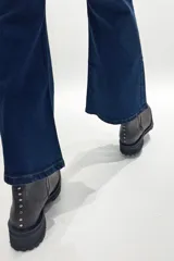 Bota de cuero color chocolate, con caña media, cierre lateral y tachas decorativas en la parte trasera.