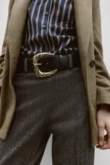 Pantalón de tiro alto con diseño de espiga, corte recto y nervio marcado en el frente. Incluye un cinturón ancho con hebilla metálica dorada y cierre lateral con cremallera oculta.
