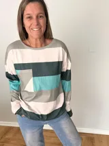 Remera de manga larga en tejido liviano con diseño de rayas anchas en tonos fucsia, gris y crudo. Corte recto y cómodo con bolsillo delantero.