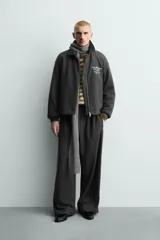 Pantalón de corte baggy fit, color gris oscuro con estampado de rayas verticales finas. Presenta cintura elástica con cordón interior, bolsillos frontales de vivo y bolsillos traseros de plastrón.