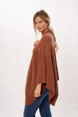 Ruana tejida de punto color marrón con etiqueta de cuero con el logo de la marca en la parte inferior.