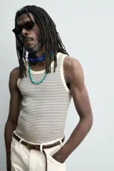 Camiseta sin mangas de corte regular, confeccionada en tejido de algodón con elasticidad. Presenta un diseño de rayas horizontales finas, cuello redondo y acabados en vivo doble.