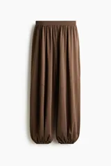 Pantalón de punto elástico color marrón, con cintura elástica fruncida y diseño de piernas globo con elástico fino en los bajos.