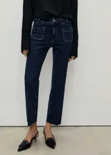 Jeans de tiro medio en denim azul oscuro, con corte flare y largo al tobillo. Presenta dos bolsillos de parche frontales, cierre de cremallera con botón y ruedo deshilachado.