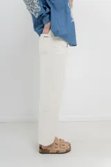 Jean de tiro alto, recto a la pierna, con cinco bolsillos, cierre frontal con cremallera y un botón. Pespunte en rosa.