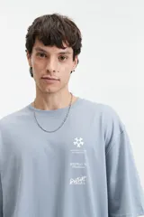 Remera marrón de manga corta con corte oversize y cuello redondo. Estampado en la espalda con diseño abstracto y texto.