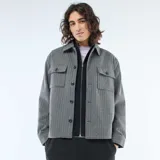 Sobrecamisa de corte recto y diseño estructurado, confeccionada en tejido gris con patrón de rayas verticales finas. Presenta cuello clásico, cierre frontal con botones y dos bolsillos frontales con solapa.