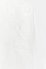 Remera blanca de manga corta y cuello redondo, de corte regular fit, con delicados detalles de bordados tonales en el frente.