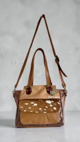 Cartera tipo tote de cuero en combinación de tonos marrones y beige, con diseño estructurado, doble asa de hombro, bolsillo frontal con solapa de pelo con estampado animal print, herrajes metálicos y llavero decorativo de la marca.