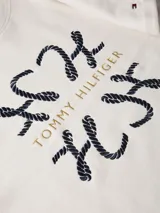 Vestido blanco de corte recto con cuello redondo y mangas cortas con dobladillo. Estampado frontal con el logo de Tommy Hilfiger con detalles de cuerdas en forma de H.