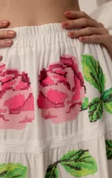 Falda larga blanca de corte en capas, con delicado bordado floral artesanal en punto de cruz con detalles en tonos rosados y verdes.