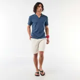 Bermuda de lino mezclado color blanco con sutiles rayas verticales oscuras, de corte clásico y bolsillos laterales.