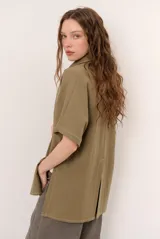 Sobrecamisa roja de lino de manga corta, con cuello solapa, costuras decorativas en contraste y cierre frontal con presillas y botones alargados.