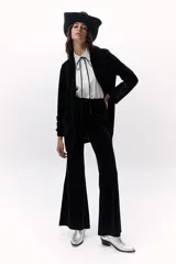 Pantalón de terciopelo negro, de tiro alto y corte acampanado.