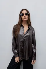 Camisa blanca de calce relajado con acabado satinado y brillo sutil, cuello clásico, cierre frontal con botones y mangas largas con puños.