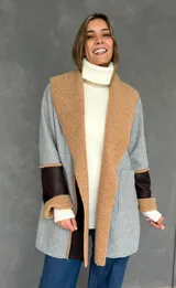 Saco de paño gris con solapas amplias de corderito color tostado. Presenta detalles de parches en cuero sintético marrón en las mangas y puños con vuelta de corderito.