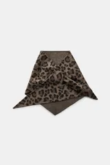 Bandana de forma triangular confeccionada en hilatura con lana, con estampado animal print en tonos marrones y cierre ajustable con ojal.