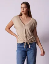 Blusa color beige de modal con escote en V, abertura central con botones y ruedo anudado. Marca French Laundry.