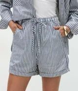 Short tipo runner de jean de algodón, con diseño de rayas verticales en azul y blanco, cintura elástica con cordón de ajuste, bolsillos laterales y dobladillo en la terminación.