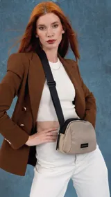 Bandolera de diseño compacto confeccionada en tafeta, con cierre superior y correa ancha ajustable de color negro. Presenta un parche con logo en el frente.