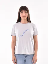 Remera de algodón color gris claro, con cuello redondo y mangas cortas. Presenta un estampado frontal con la frase 'Ride the wave' en letras azules con contorno.