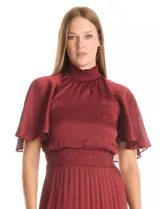 Vestido midi de satén color beige, con cuello alto fruncido, mangas cortas fluidas y cintura elástica tipo smock. Presenta una falda plisada con caída fluida y forro interno.