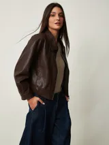 Campera corta de cuero sintético marrón chocolate con cuello camisero, cierre frontal de cremallera y diseño holgado.