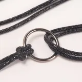 Cinto fino negro con brillo, con hebilla de argolla metálica plateada y detalle de nudo.