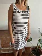 Camisón corto sin mangas, ajustado al cuerpo, con estampado de rayas horizontales blancas y negras. Presenta un cuello redondo con un detalle de volado fruncido en el borde.